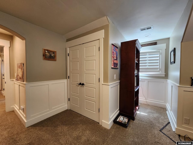 303 Tamarack Dr, Rock Springs, WY 82901 - hallway with carpet flooring, a wainscoted wall, arched walkways, visible vents, and a decorative wall