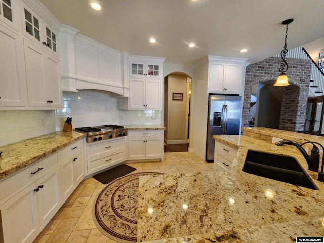 303 Tamarack Dr, Rock Springs, WY 82901 - kitchen featuring a sink, stainless steel appliances, white cabinets, arched walkways, and decorative backsplash