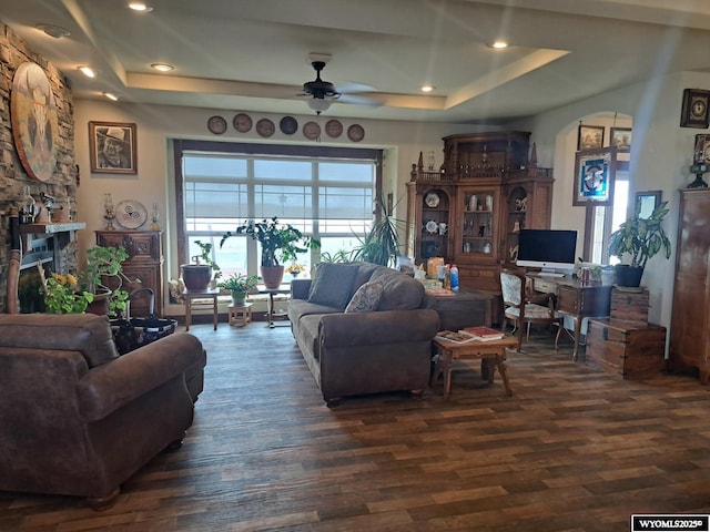 37 Winchester Rd, Guernsey, WY 82214 - living area with a tray ceiling, a stone fireplace, ceiling fan, and dark wood-style flooring