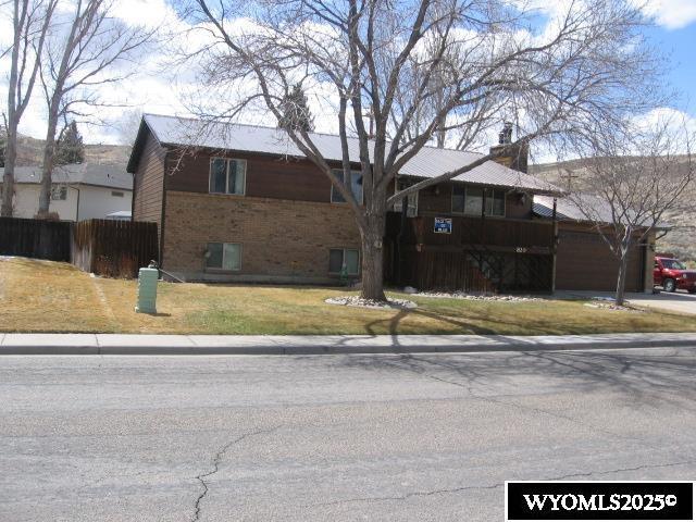 view of front of house featuring a chimney, fence, a front lawn, and brick siding