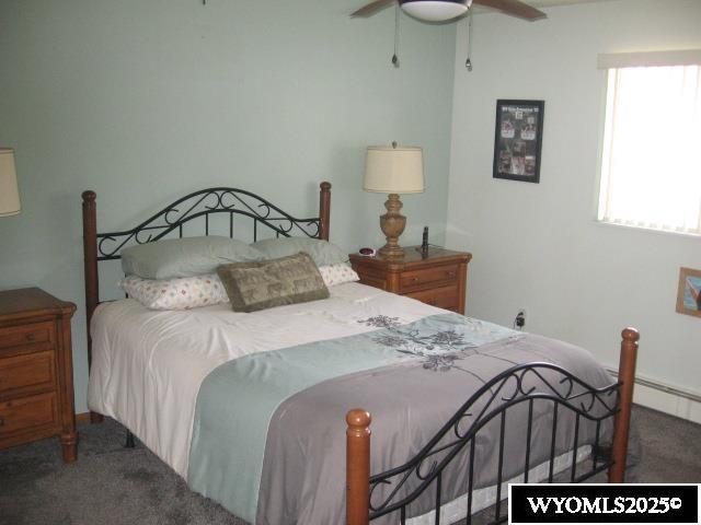 carpeted bedroom featuring ceiling fan and baseboard heating