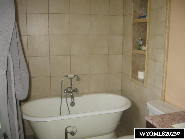 bathroom with tile walls, a freestanding tub, and vanity
