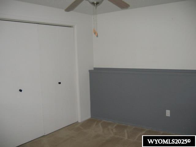 unfurnished bedroom with carpet flooring, a closet, and ceiling fan