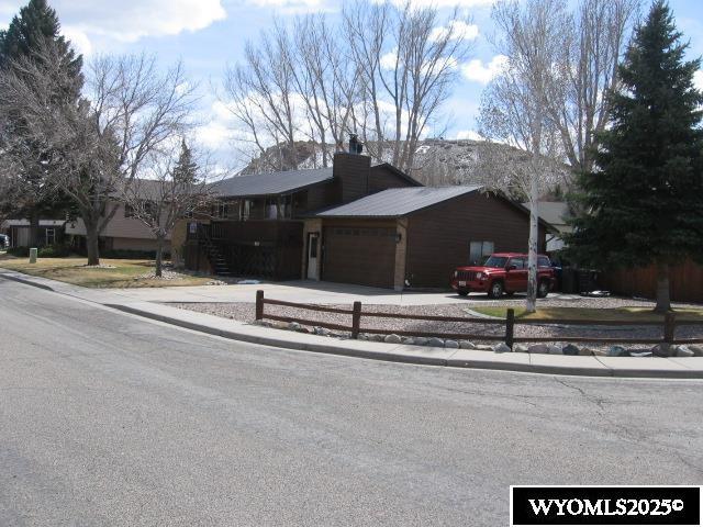 view of front of home featuring driveway, an attached garage, a chimney, and stairway