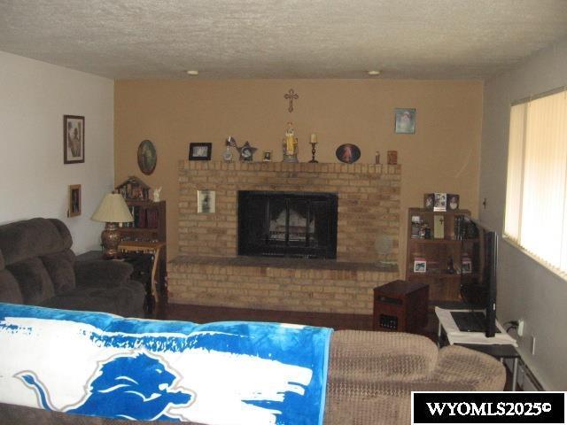 living room featuring a brick fireplace and a textured ceiling