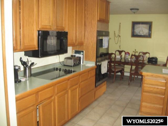 kitchen with light countertops, light tile patterned floors, and black appliances