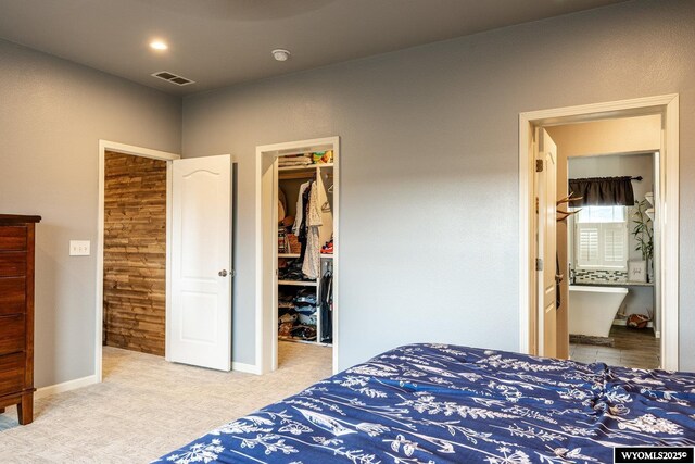 carpeted bedroom featuring a closet, a walk in closet, ensuite bath, baseboards, and visible vents