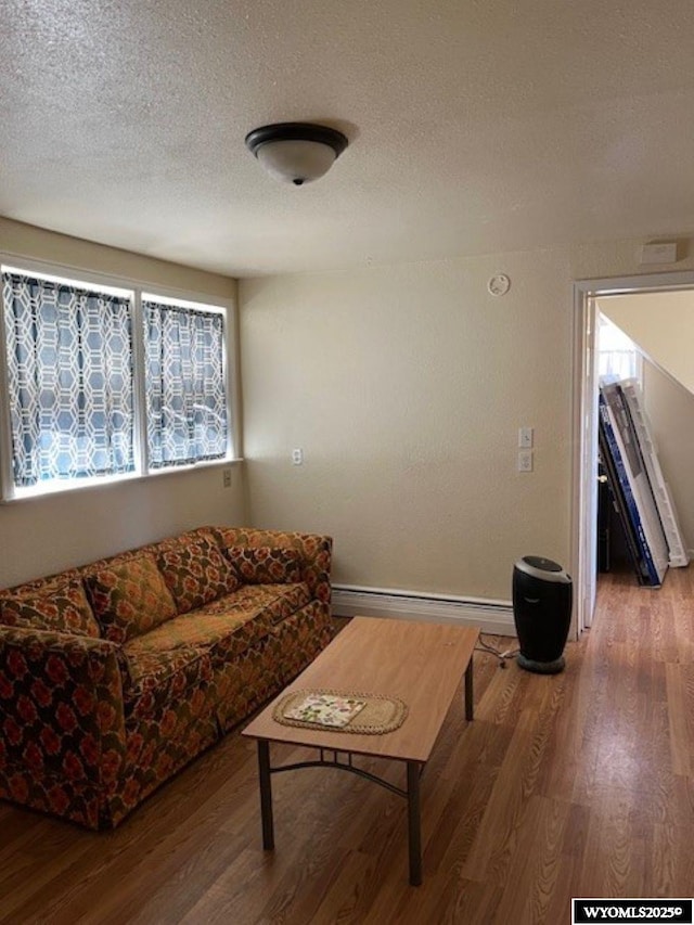 419 6th St, Rawlins, WY 82301 - living room featuring baseboards, wood finished floors, a baseboard heating unit, and a textured ceiling