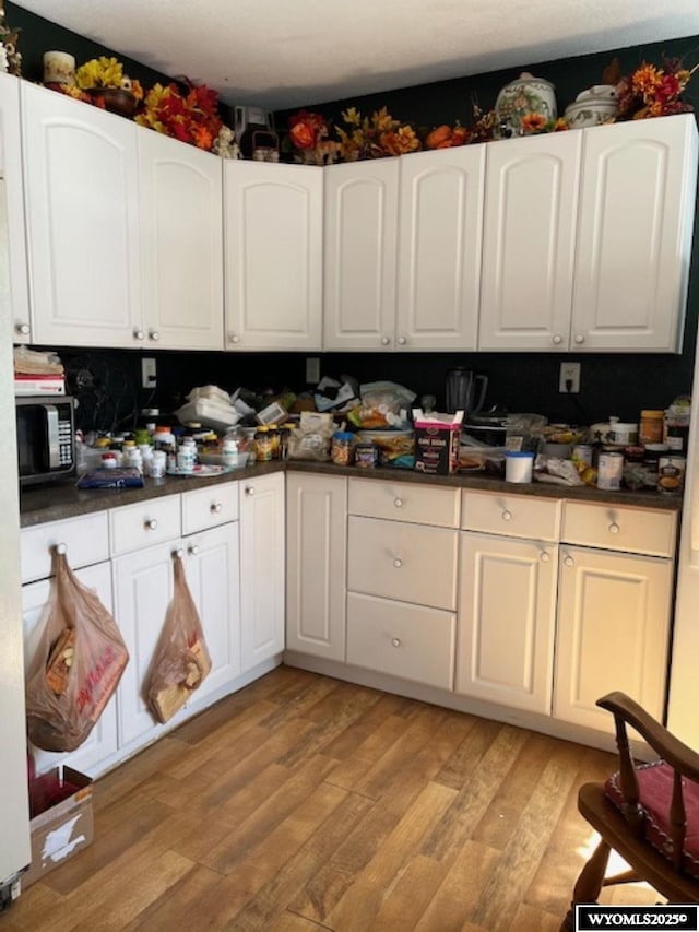 419 6th St, Rawlins, WY 82301 - kitchen featuring white cabinetry, dark countertops, and light wood finished floors