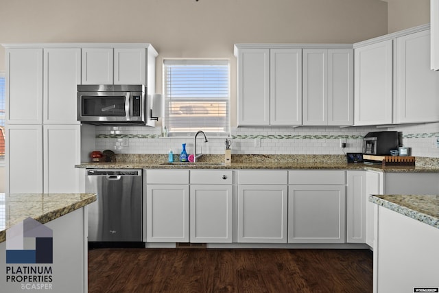 kitchen featuring light stone countertops, white cabinetry, a sink, and appliances with stainless steel finishes