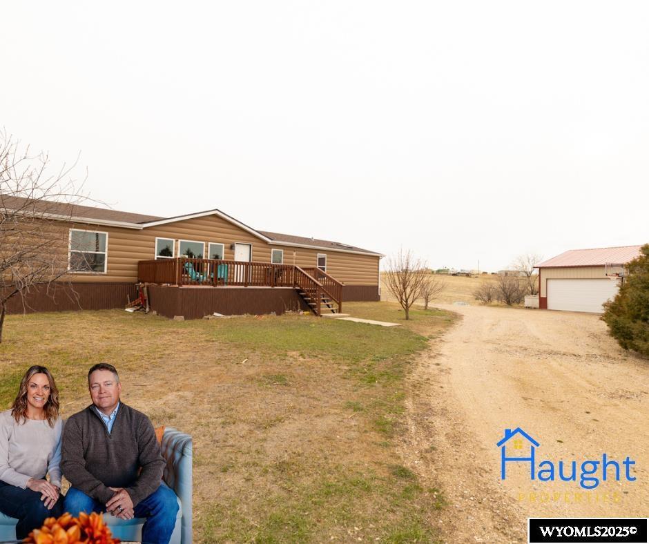 12 Overhil Trl, Douglas, WY 82633 - view of front of house featuring a wooden deck, a front yard, a garage, driveway, and stairway