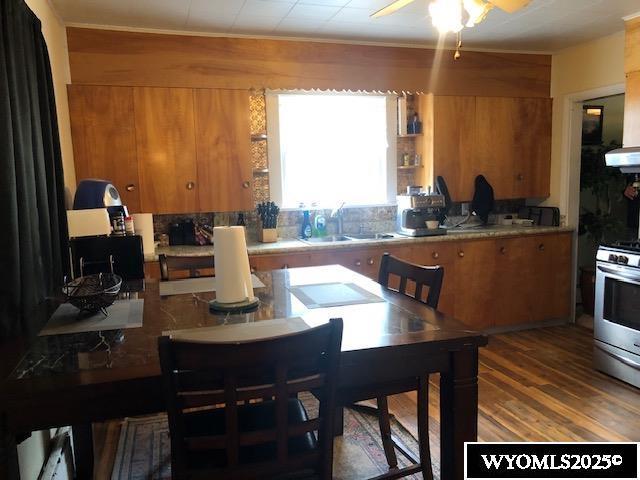 816 Center St, Rock Springs, WY 82901 - kitchen with stainless steel range with gas cooktop, brown cabinets, decorative backsplash, a sink, and wood finished floors