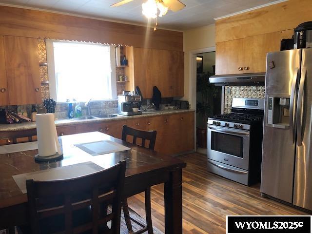 816 Center St, Rock Springs, WY 82901 - kitchen featuring tasteful backsplash, a sink, appliances with stainless steel finishes, under cabinet range hood, and wood finished floors
