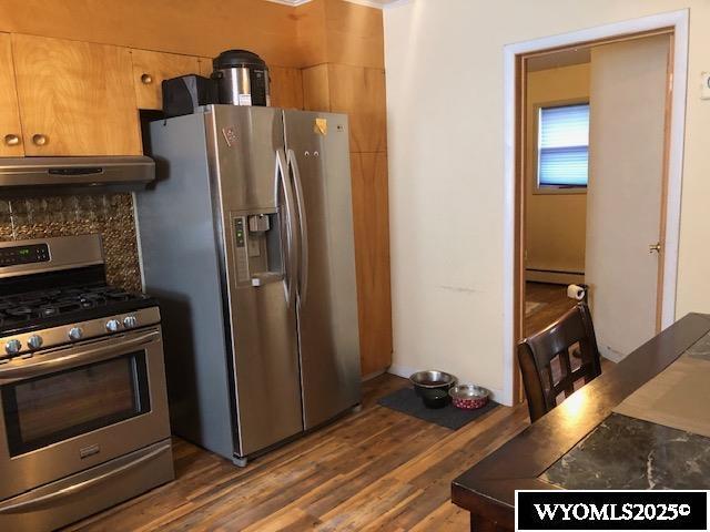 816 Center St, Rock Springs, WY 82901 - kitchen with under cabinet range hood, a baseboard radiator, dark wood finished floors, and appliances with stainless steel finishes
