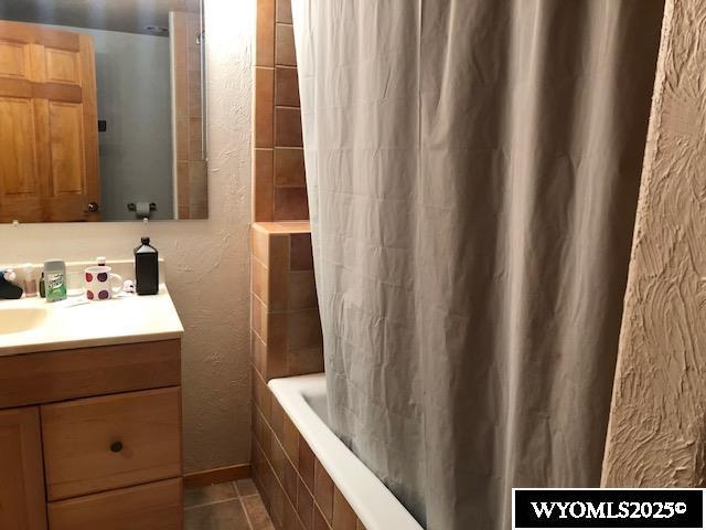 816 Center St, Rock Springs, WY 82901 - full bath featuring a textured wall, tile patterned floors, vanity, and tiled shower / bath combo