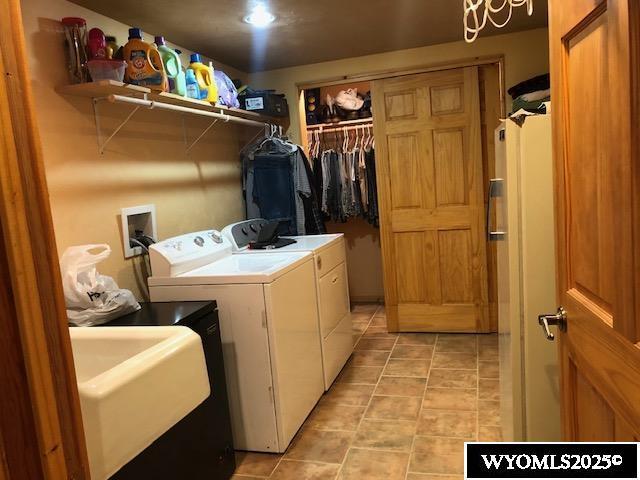 816 Center St, Rock Springs, WY 82901 - clothes washing area featuring a sink, washing machine and clothes dryer, light tile patterned flooring, and laundry area
