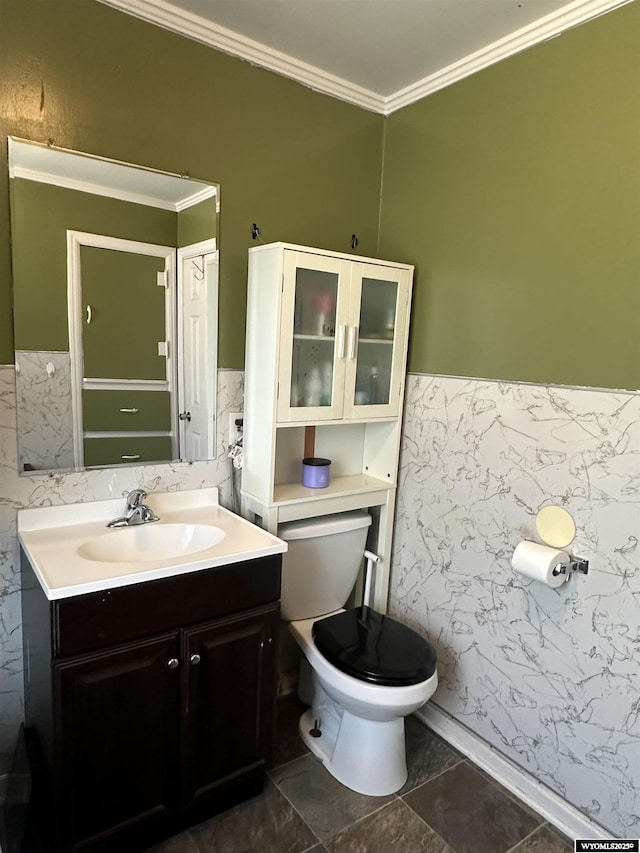 half bath with crown molding, vanity, a wainscoted wall, toilet, and tile walls