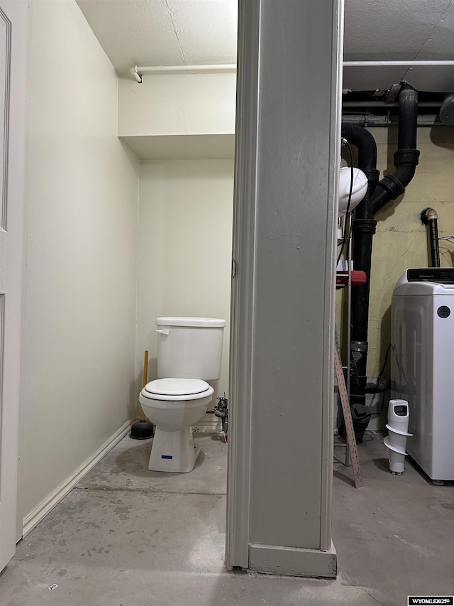 bathroom with toilet, concrete floors, washer / dryer, and water heater
