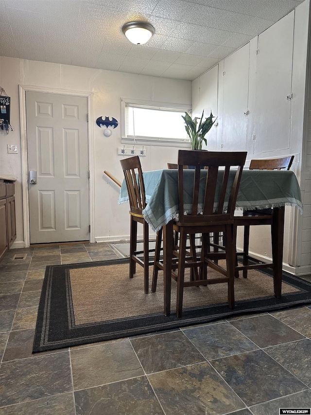 dining room featuring stone tile floors and baseboards