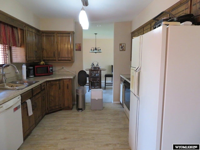 1001 Cheshire St, Casper, WY 82609 - kitchen featuring white appliances, light wood-style flooring, light countertops, a sink, and decorative light fixtures
