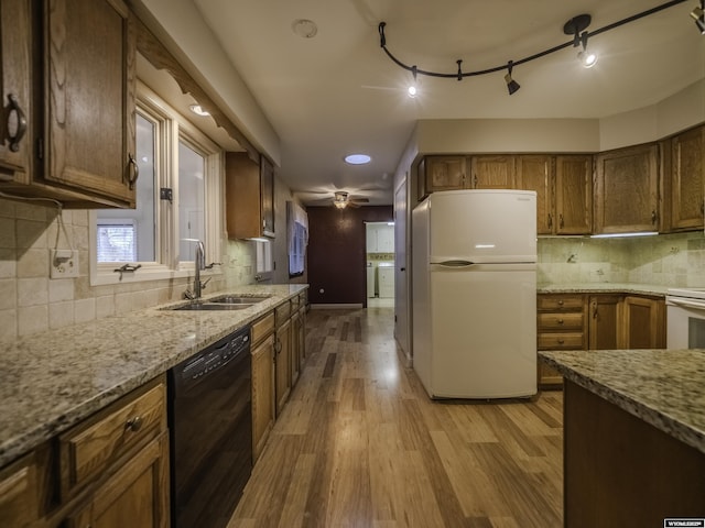 kitchen featuring white appliances, light stone countertops, tasteful backsplash, wood finished floors, and a sink