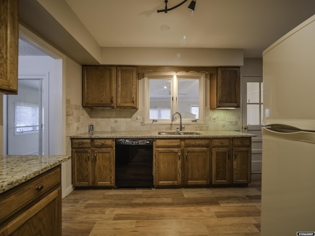 kitchen with tasteful backsplash, a sink, freestanding refrigerator, and black dishwasher