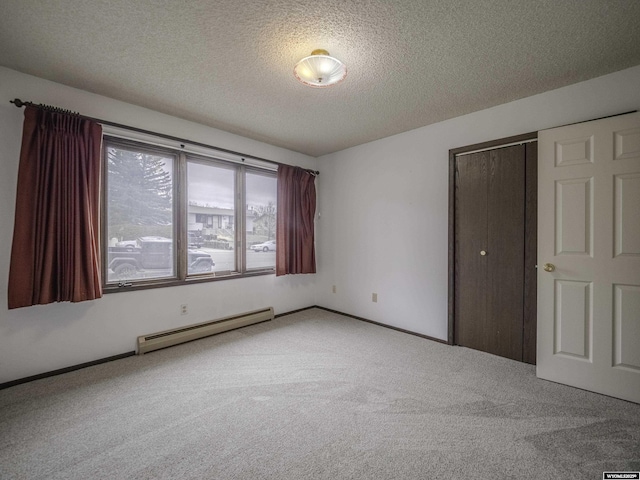 unfurnished bedroom featuring baseboard heating, baseboards, a closet, carpet flooring, and a textured ceiling