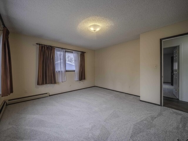 carpeted spare room with baseboards, a baseboard heating unit, and a textured ceiling