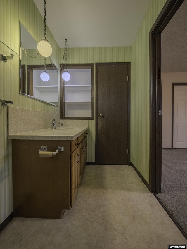 bathroom with vanity, baseboards, and wallpapered walls