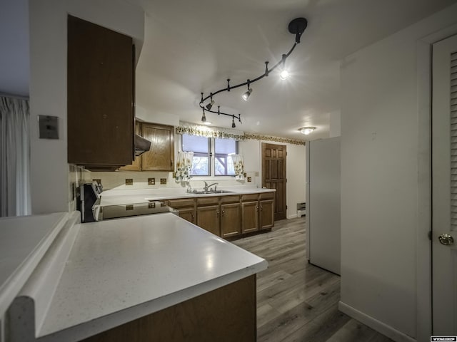 kitchen with freestanding refrigerator, stove, light wood-type flooring, light countertops, and a sink