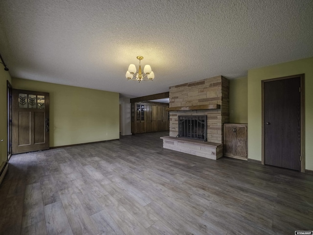 unfurnished living room with baseboards, a large fireplace, a chandelier, a textured ceiling, and dark wood-type flooring
