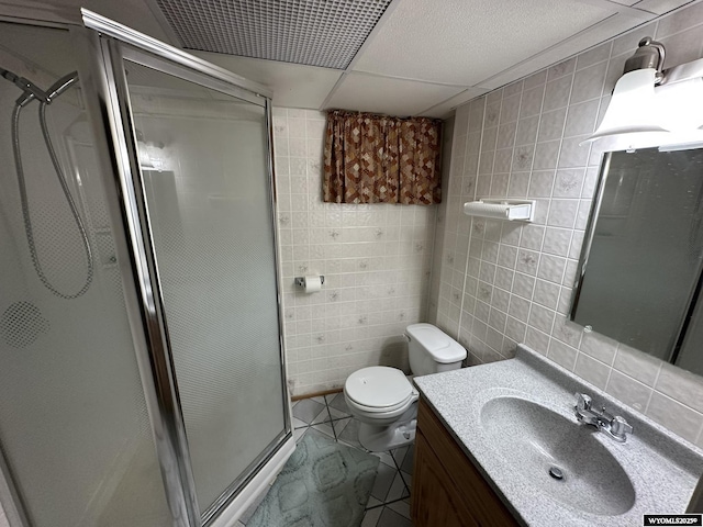 341 E 29th Ave, Torrington, WY 82240 - full bath featuring toilet, tile walls, vanity, a drop ceiling, and a stall shower