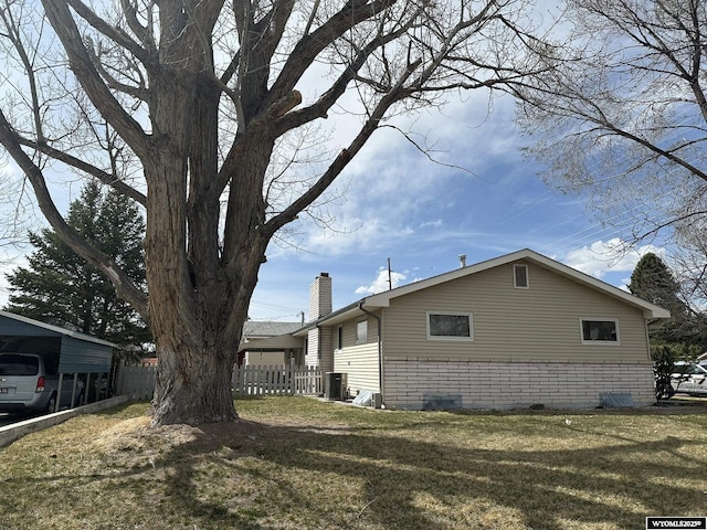 341 E 29th Ave, Torrington, WY 82240 - view of side of home featuring central AC, a chimney, fence, and a lawn