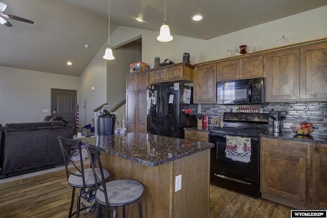 kitchen featuring tasteful backsplash, black appliances, a kitchen bar, and dark wood finished floors
