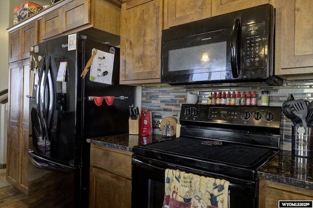 kitchen with black appliances, backsplash, and dark stone counters