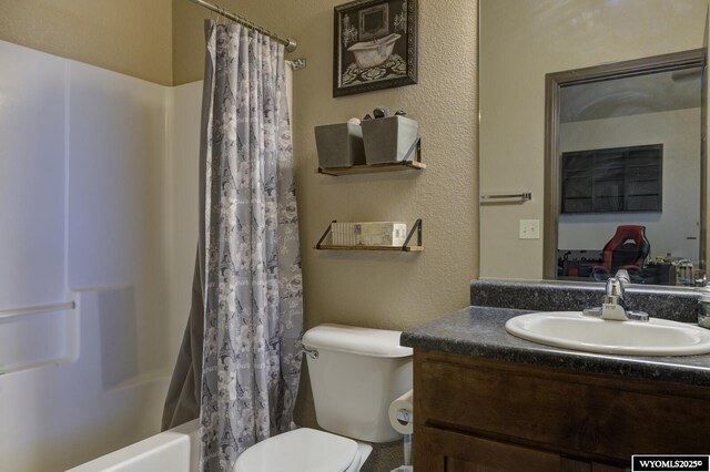 full bath with shower / bath combo, vanity, toilet, and a textured wall