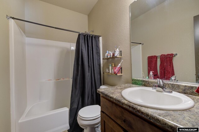 full bath with toilet, shower / bathtub combination with curtain, vanity, and a textured wall