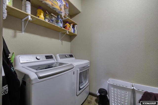 clothes washing area with laundry area, a textured wall, and washer and clothes dryer