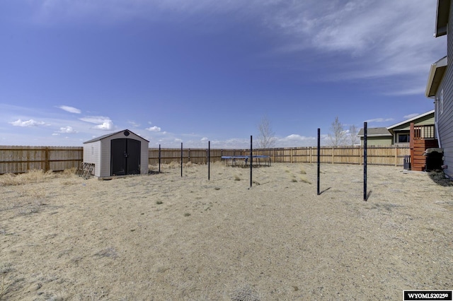 view of yard featuring a storage shed, an outbuilding, a fenced backyard, and a trampoline