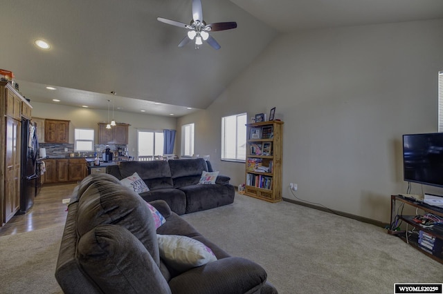 living room featuring baseboards, ceiling fan, recessed lighting, high vaulted ceiling, and light carpet