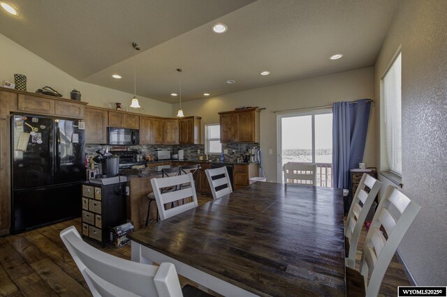 kitchen with tasteful backsplash, a center island, dark countertops, black appliances, and dark wood-type flooring
