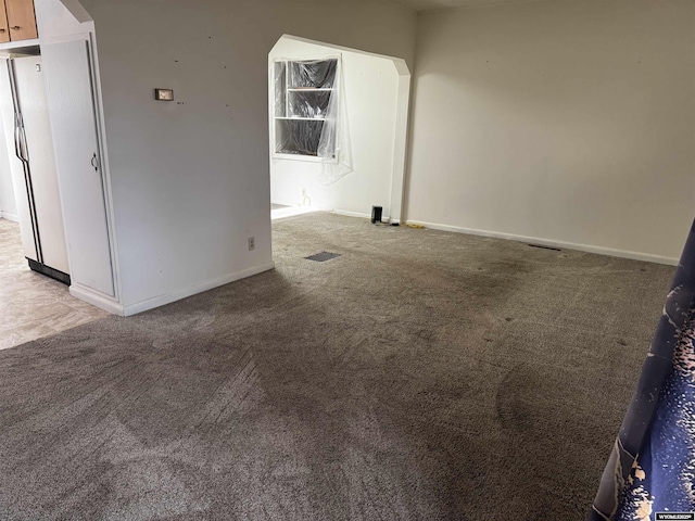 carpeted spare room featuring baseboards, arched walkways, and visible vents