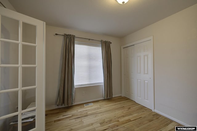 unfurnished bedroom featuring a closet, baseboards, light wood-type flooring, and visible vents