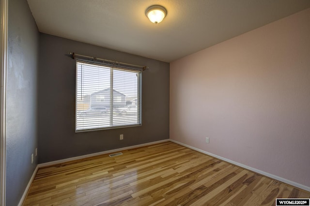 spare room with visible vents, baseboards, and light wood finished floors