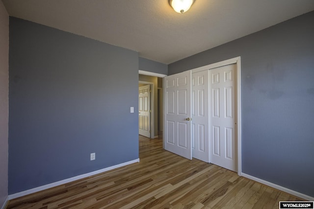 unfurnished bedroom with a closet, baseboards, and wood finished floors