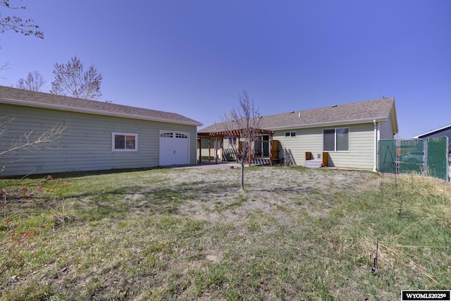 back of house with a garage, a yard, and fence