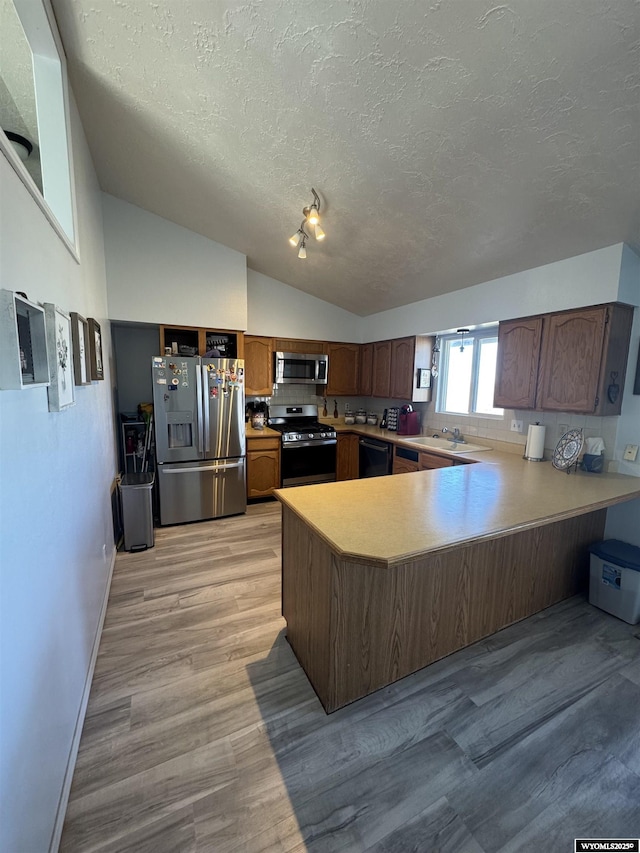325 Hathaway Ave, Evanston, WY 82930 - kitchen with a peninsula, light countertops, a textured ceiling, lofted ceiling, and appliances with stainless steel finishes