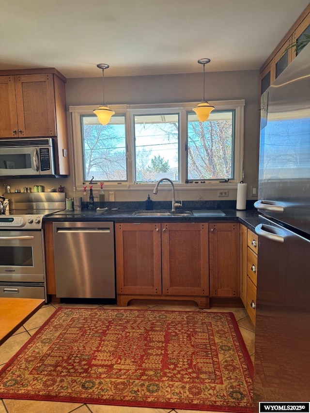 kitchen with stainless steel appliances, decorative light fixtures, brown cabinets, and a sink