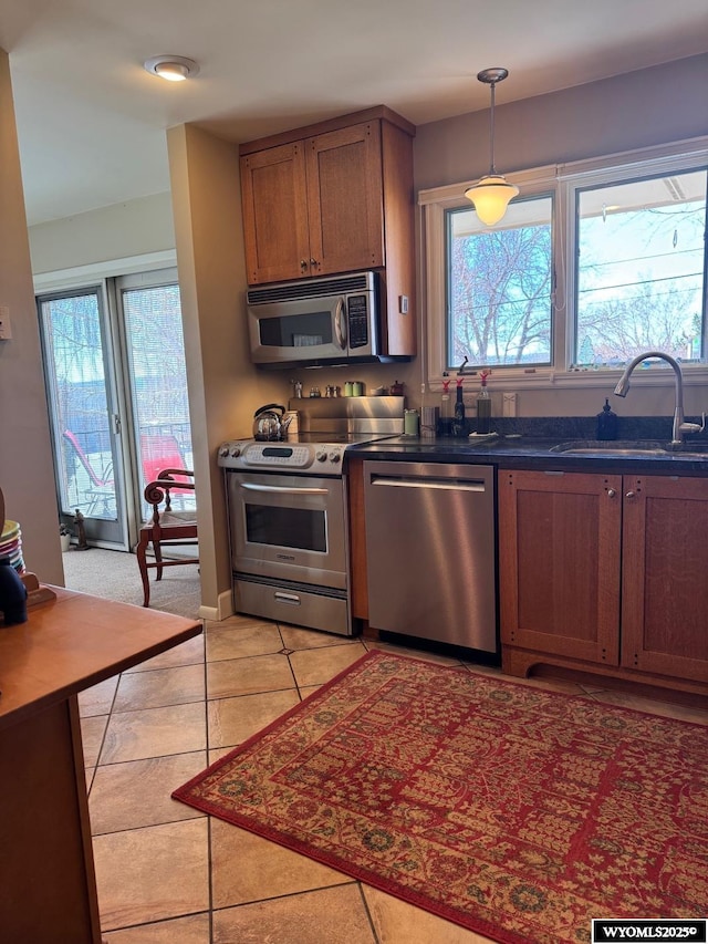 kitchen featuring a wealth of natural light, dark countertops, a sink, and appliances with stainless steel finishes