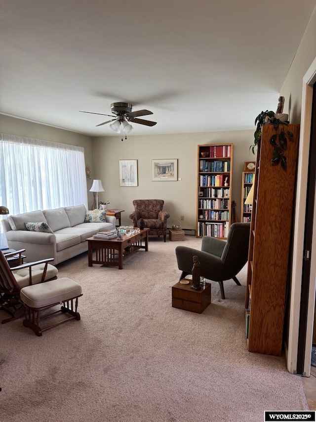 living area with a baseboard heating unit, ceiling fan, and carpet floors